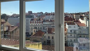 A view of a cityscape through a window with multiple panes, featuring a variety of buildings with different architectural styles and colors. - Studio 59 Lisboa (Lisbon)