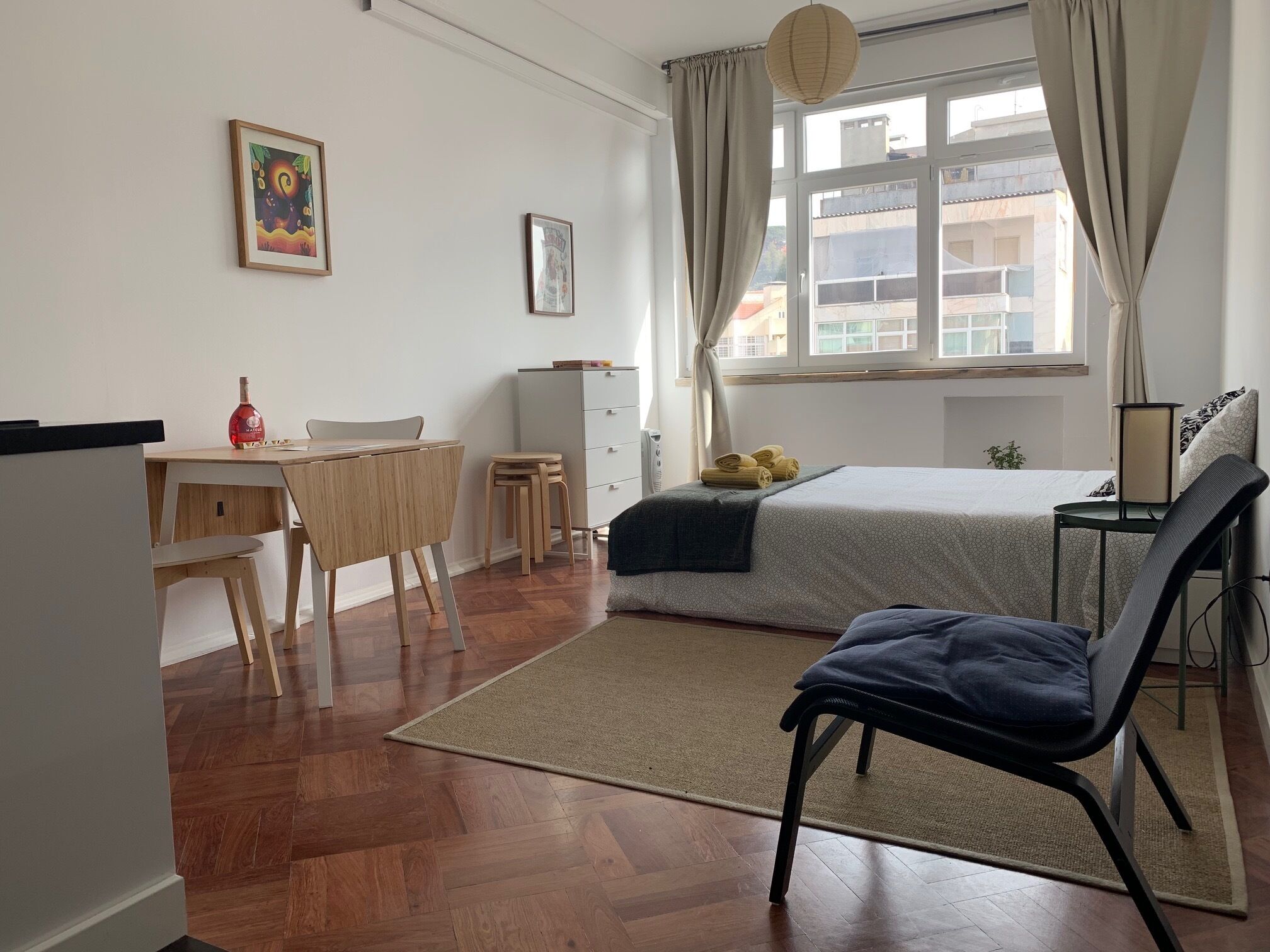 A modern bedroom with a bed, a desk, a chair, and a small table.