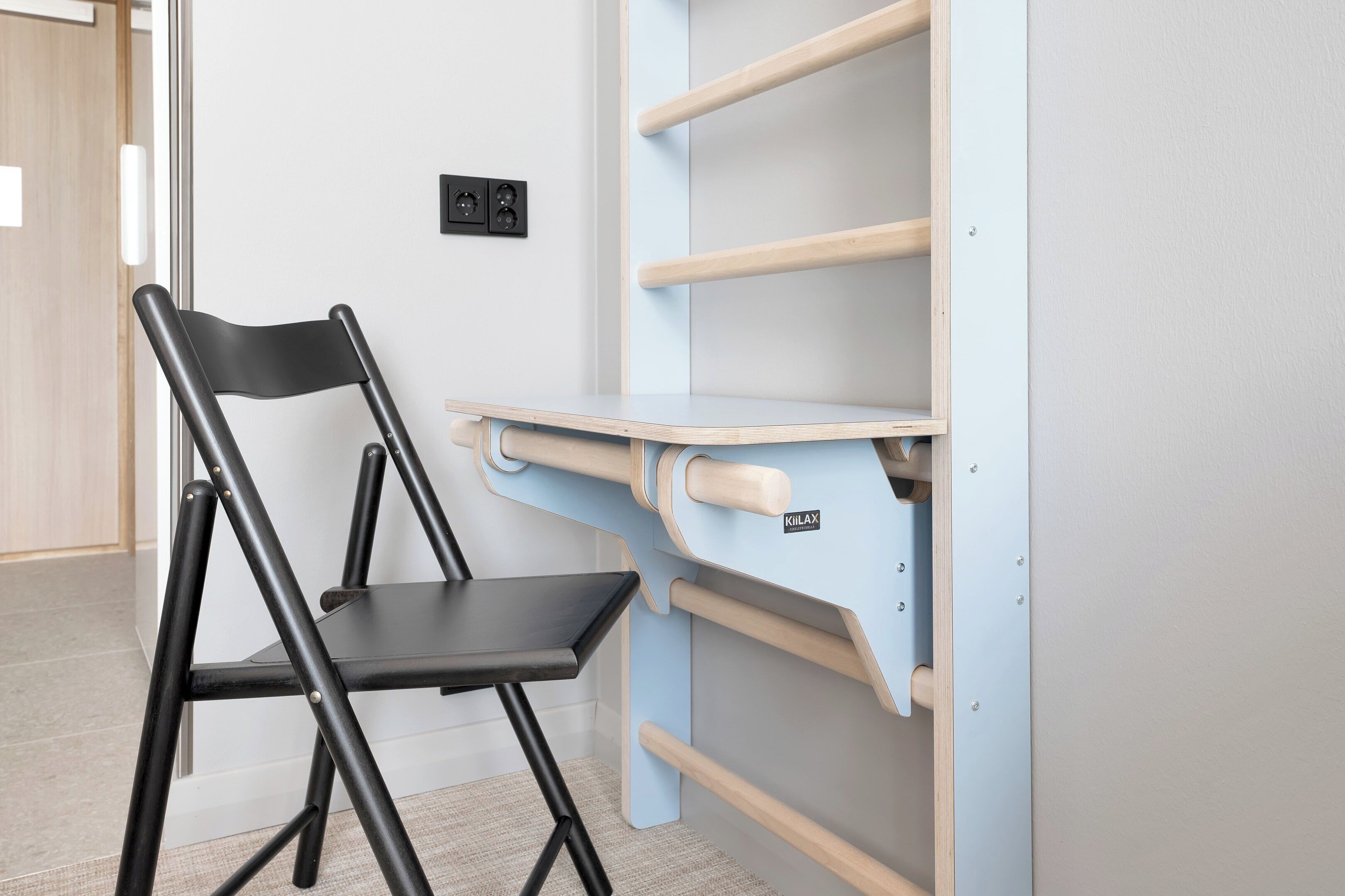 Une pièce équipée d’une chaise pliante, d’une étagère fixée au mur et d’un interrupteur.