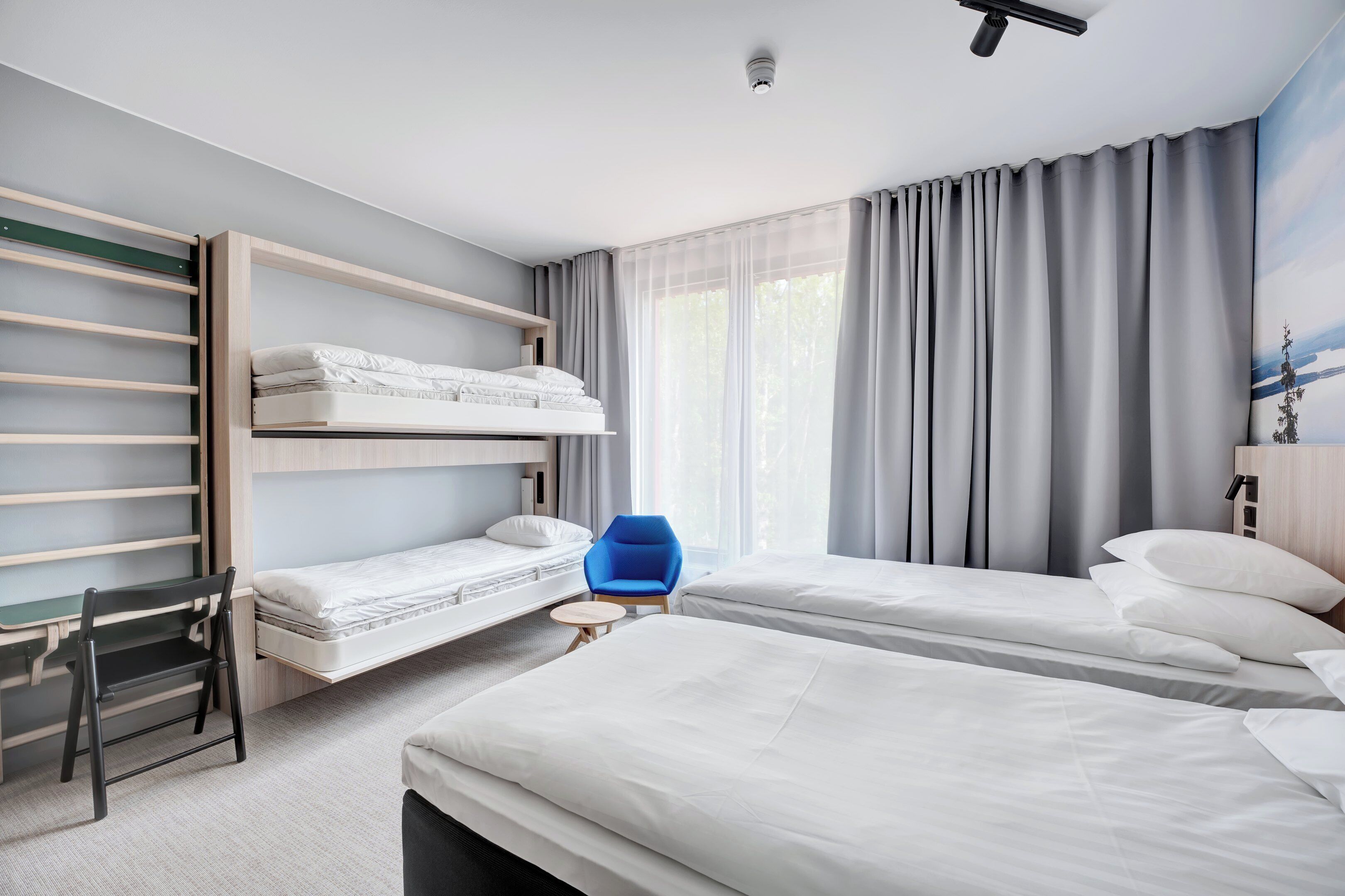 Ett modernt hotellrum med våningssängar, ett skrivbord och en stol.