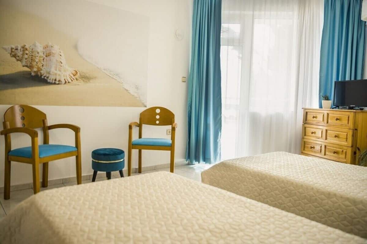 A hotel room with two beds, a wooden dresser, a television, and a painting of a seashell on the wall.