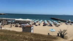 A beach with umbrellas, lounge chairs, and a pier extending into the water. - Panorama-apartmentsChantall (Ravda)