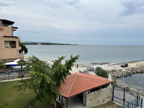 Un hotel costero con techo de tejas rojas, vistas al mar y una zona de estacionamiento.