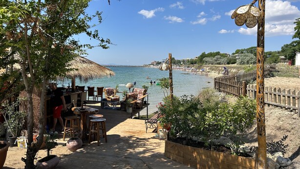 A beachside patio with outdoor seating, a thatched umbrella, and a view of the sea. - Panorama-apartmentsChantall (Ravda)
