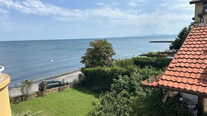 A coastal view with a clear sky, a body of water, and a building with a red-tiled roof. - Panorama-apartmentsChantall (Ravda)
