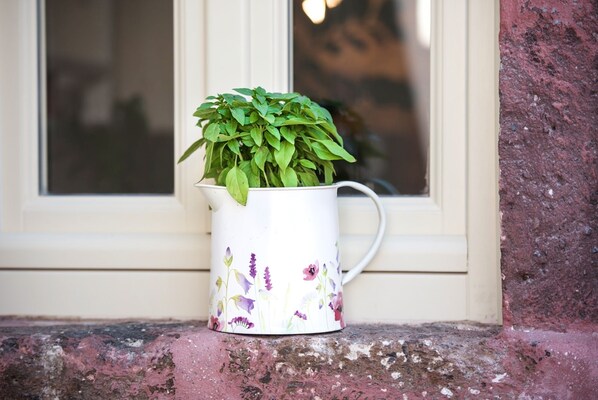 Uma caneca de cerâmica branca com desenhos florais sobre um parapeito de pedra.