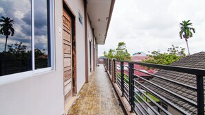 A narrow balcony with a tiled floor, a wooden door, and a metal railing. - Hotel O Oklahoma Homestay Syariah (Pekanbaru)