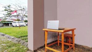 A small wooden table with a laptop on it, positioned against a wall. - Hotel O Oklahoma Homestay Syariah (Pekanbaru)