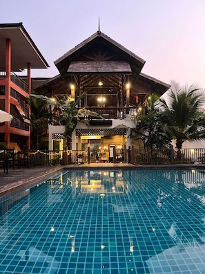 Un hôtel doté d’une piscine, d’un espace extérieur couvert et d’un immeuble à plusieurs étages avec des balcons.