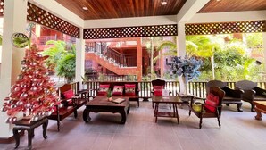 A covered outdoor seating area with wooden furniture and a Christmas tree. - Rainforest Huahin Village Hotel (Hua Hin)