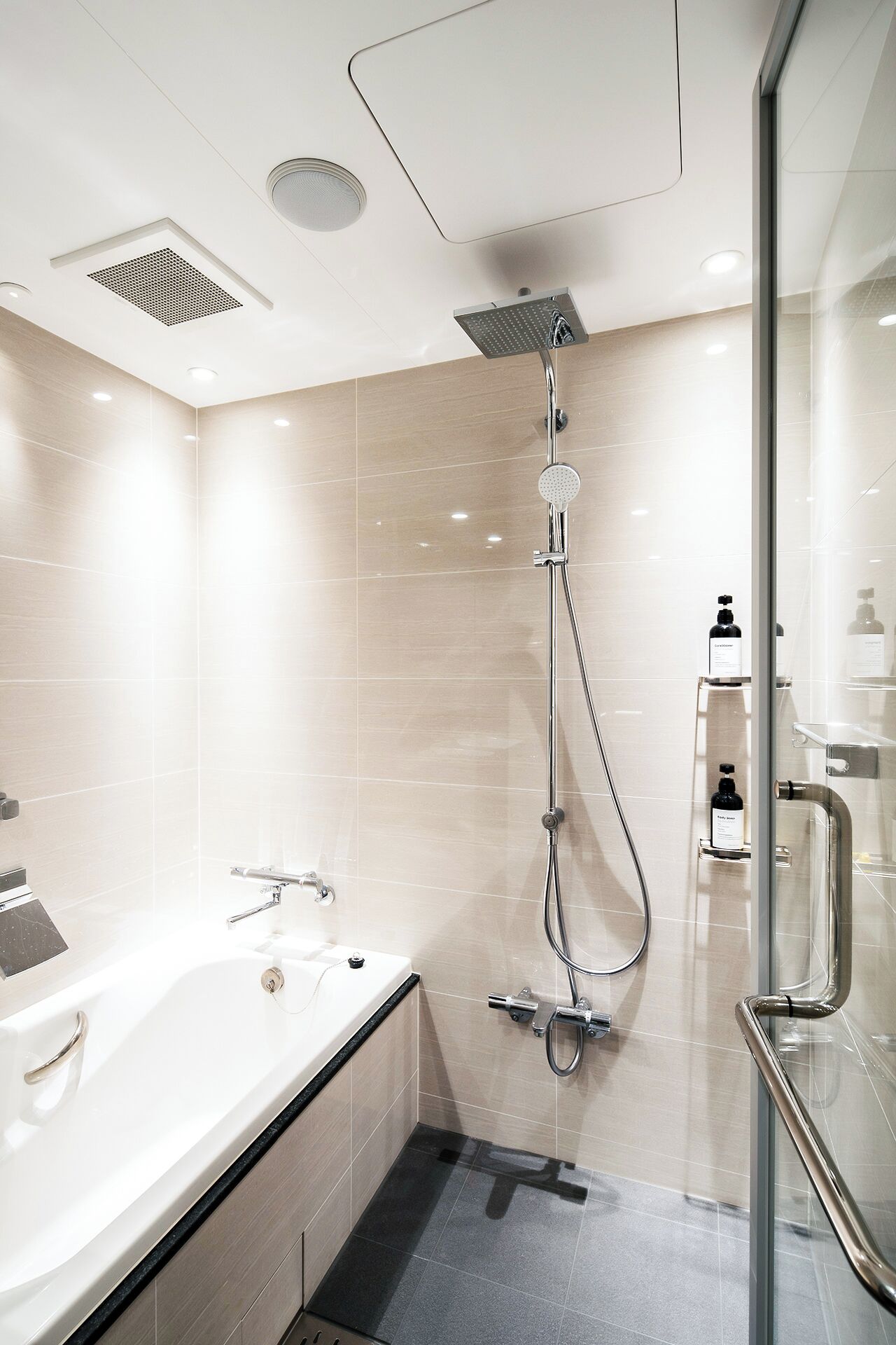A modern bathroom with a bathtub, a shower with a handheld showerhead, and a glass-enclosed shower stall.
