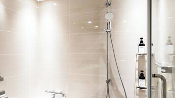 A modern bathroom with a bathtub, a shower with a handheld showerhead, and a glass-enclosed shower stall.