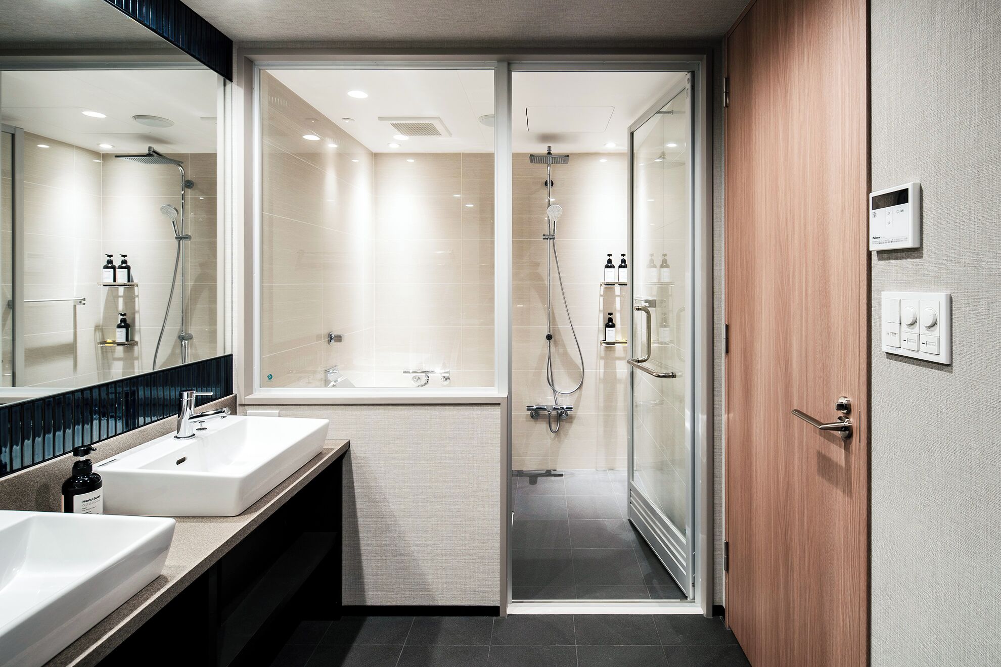 Un baño moderno con dos lavamanos, ducha y cabina de ducha con paredes de vidrio.