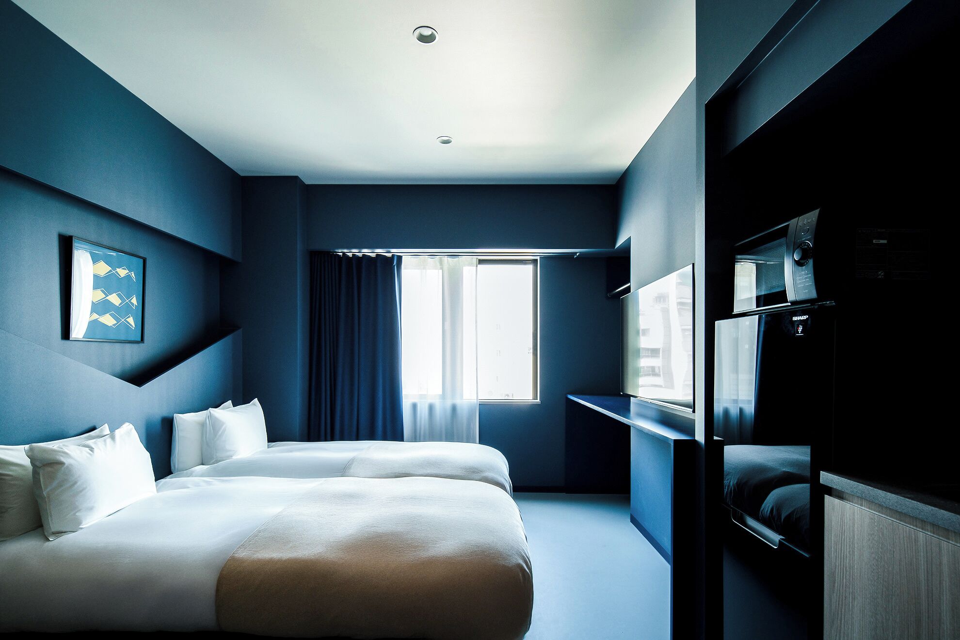Una habitación de hotel con cama, televisión y ventana con cortinas.