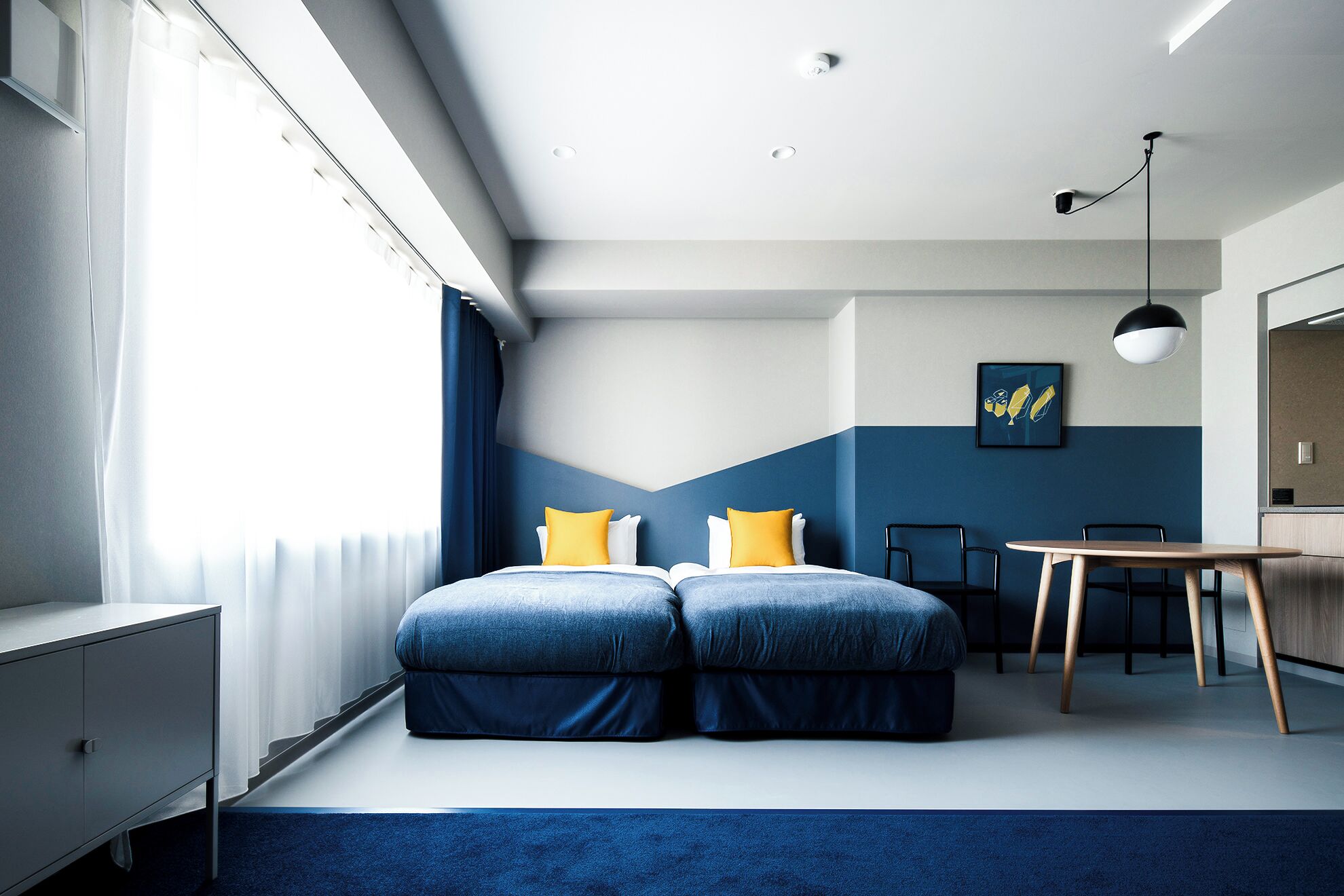 A modern hotel room with a bed, a desk, and a chair.