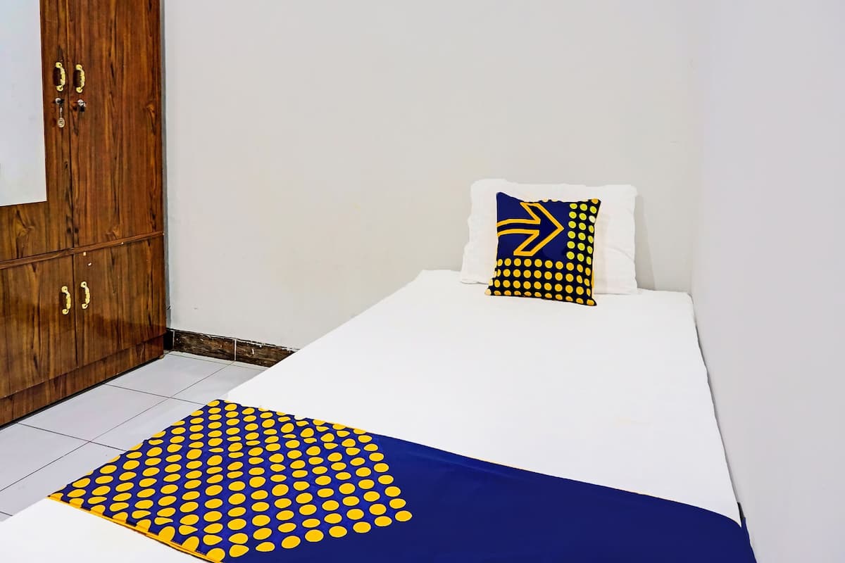 A bedroom with a bed, a wooden wardrobe, and a patterned throw on the bed.