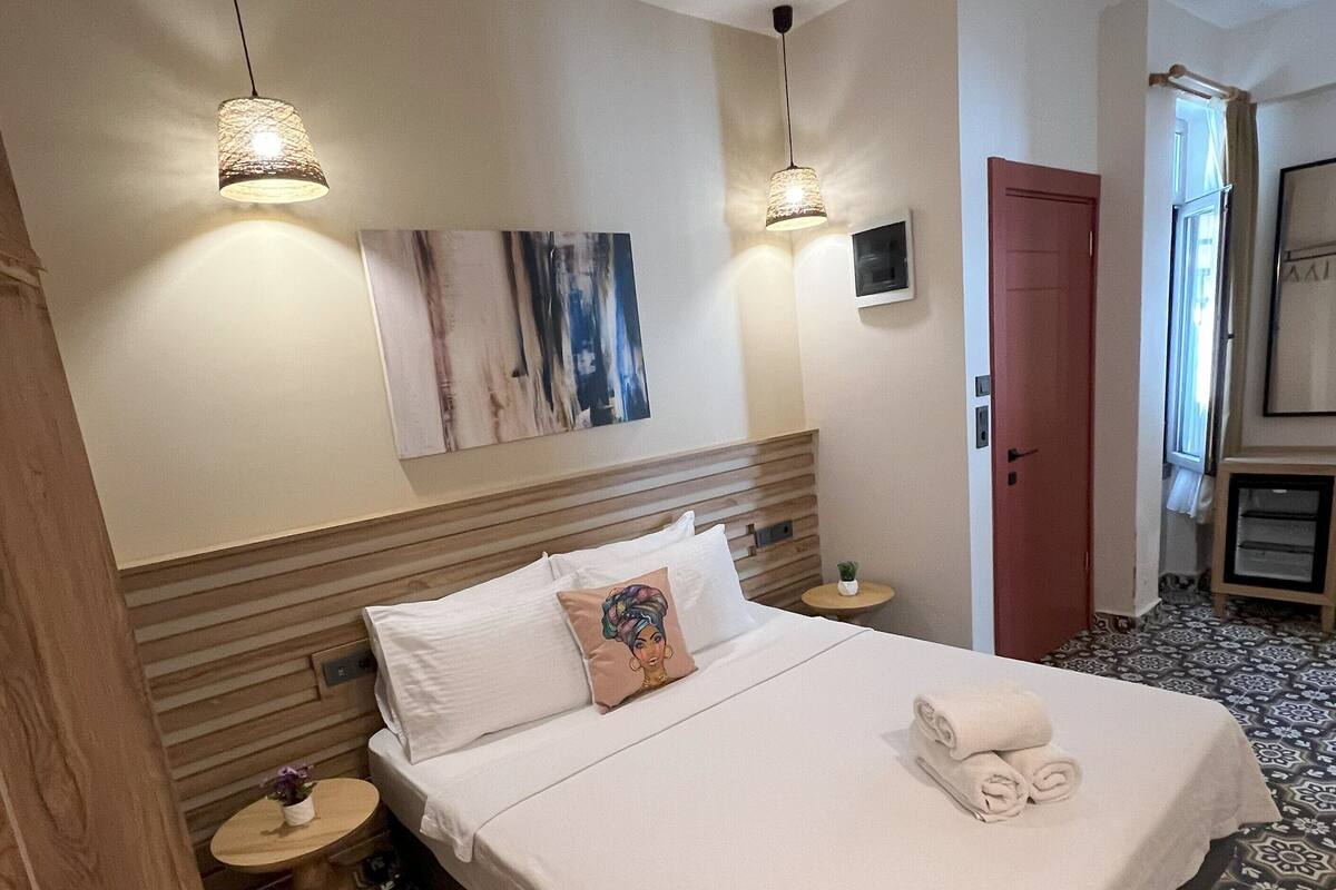 Une chambre d’hôtel avec un grand lit, deux tables de chevet, un téléviseur fixé au mur et des carreaux de sol à motifs.