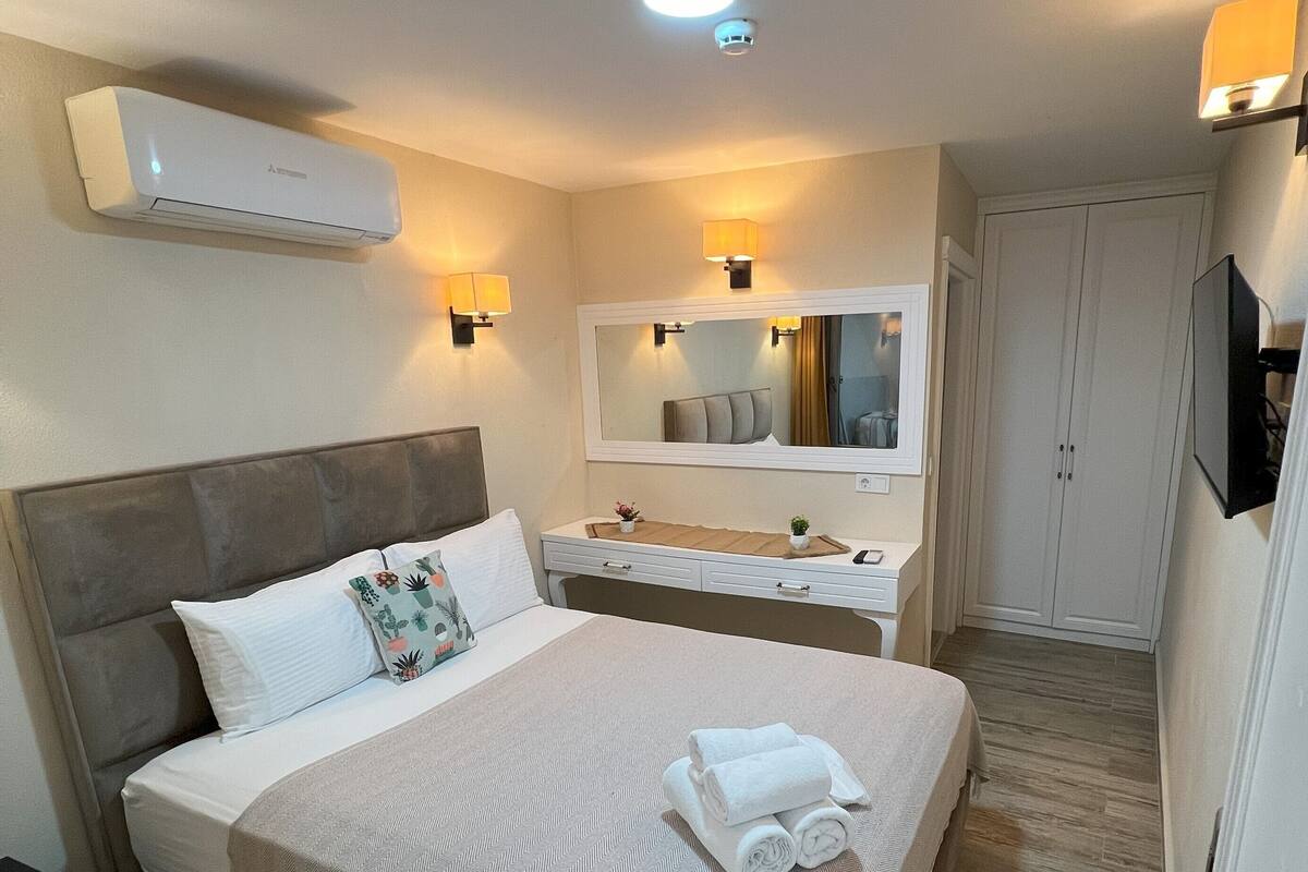 Une chambre d’hôtel comprenant un lit, une table de chevet, un miroir, une armoire et un téléviseur.