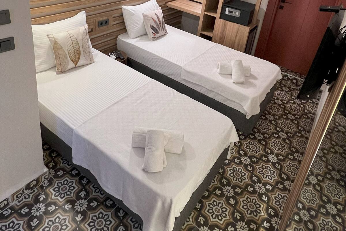 Une chambre d’hôtel avec deux lits, une armoire, un miroir et un sol à motifs.