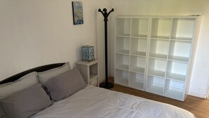 Une chambre à coucher avec un lit, une table de chevet, une lampe, une armoire et un tableau au mur.