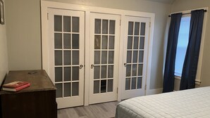 A bedroom with a bed, a dresser, and a set of double doors. - 2-Bedroom Apt Sleeps 7! - 1/4 mile to Beach! (Hampton)