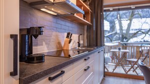 Eine moderne Küche mit Kaffeemaschine, einem Messerblock und Blick auf den Balkon.