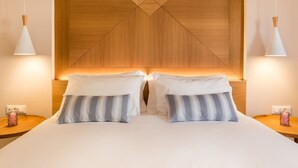 A neatly made bed with two pillows, a wooden headboard with a geometric design, and two bedside lamps.