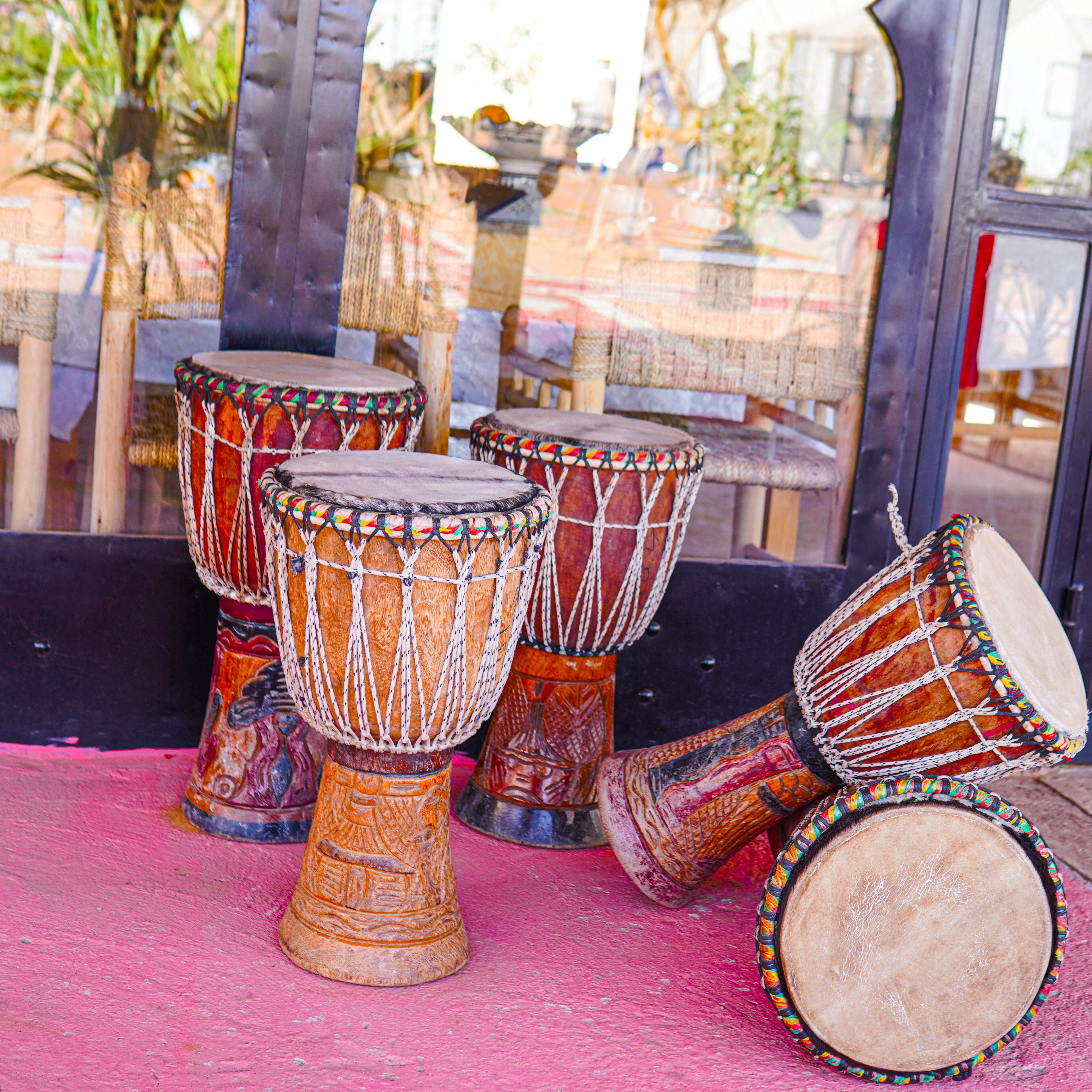 Un conjunto de tambores djembe sobre una superficie rosa.