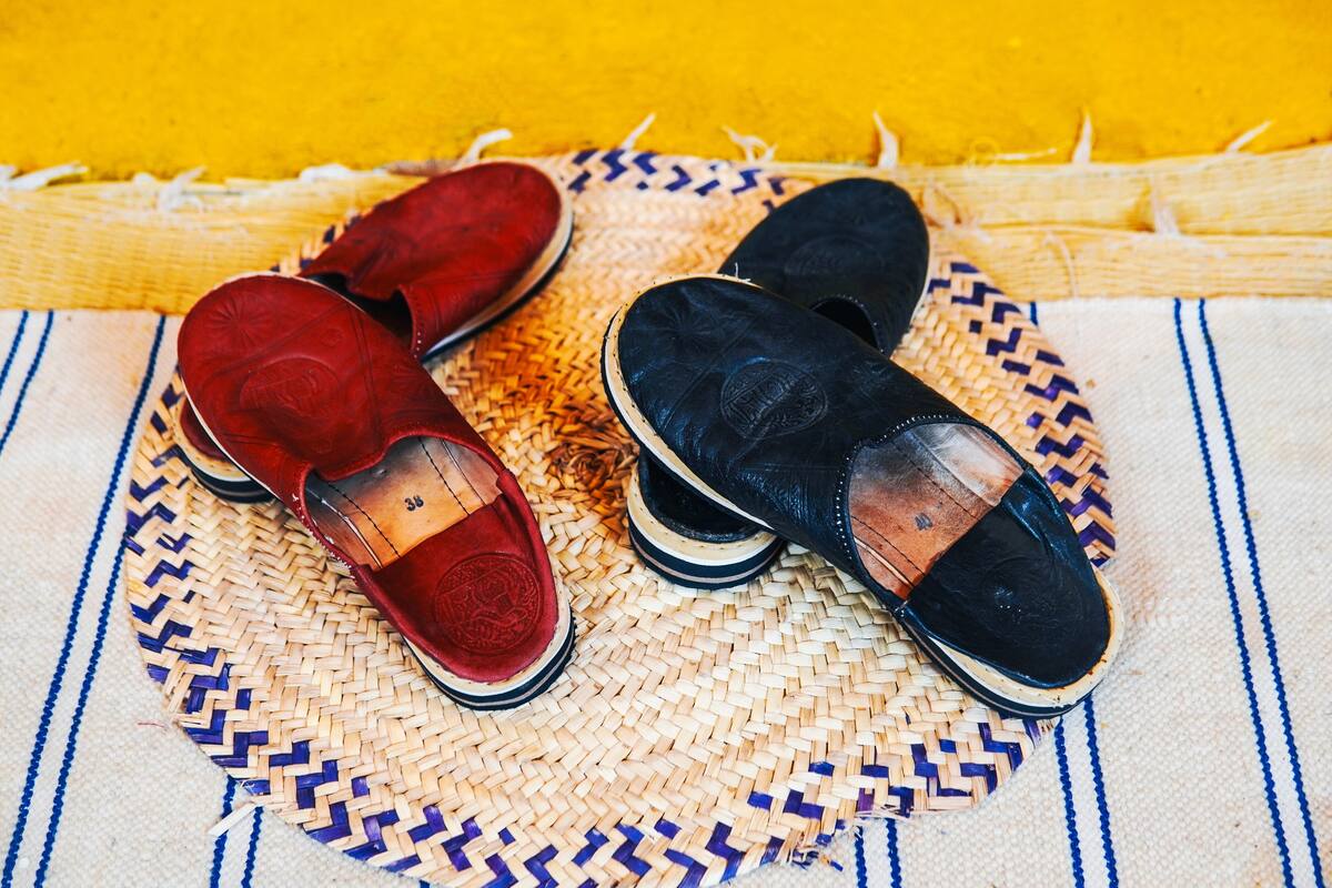A pair of red and black shoes on a woven mat.