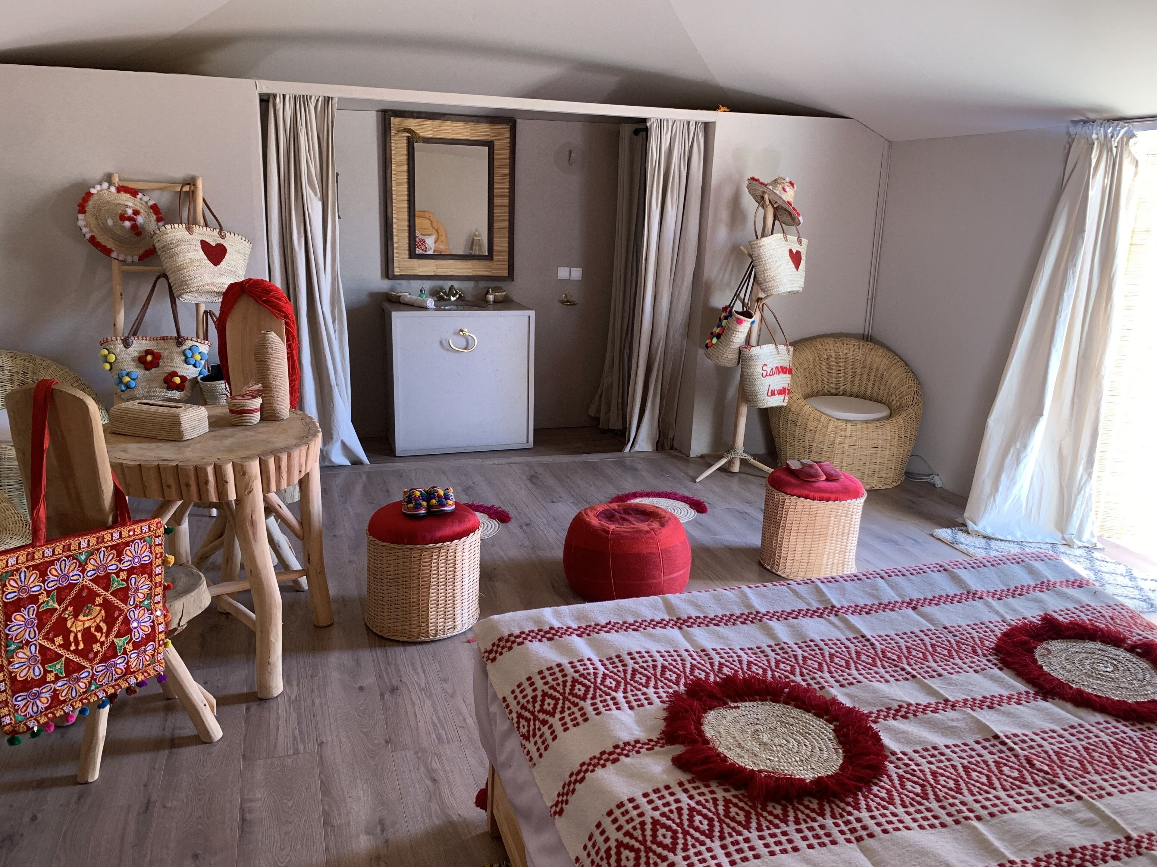 A cozy hotel room with a bed, a wicker chair, a small table, and a dresser.