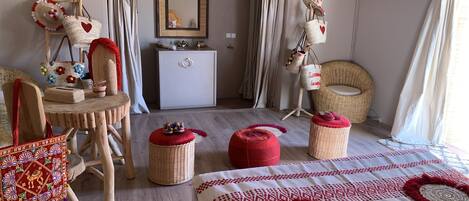 A cozy hotel room with a bed, a wicker chair, a small table, and a dresser.