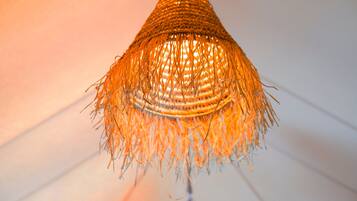 A close-up of a woven, conical light fixture with a warm glow.