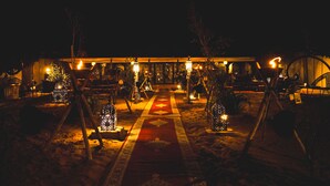 A nighttime outdoor area with a pathway, decorative lanterns, and a building in the background.