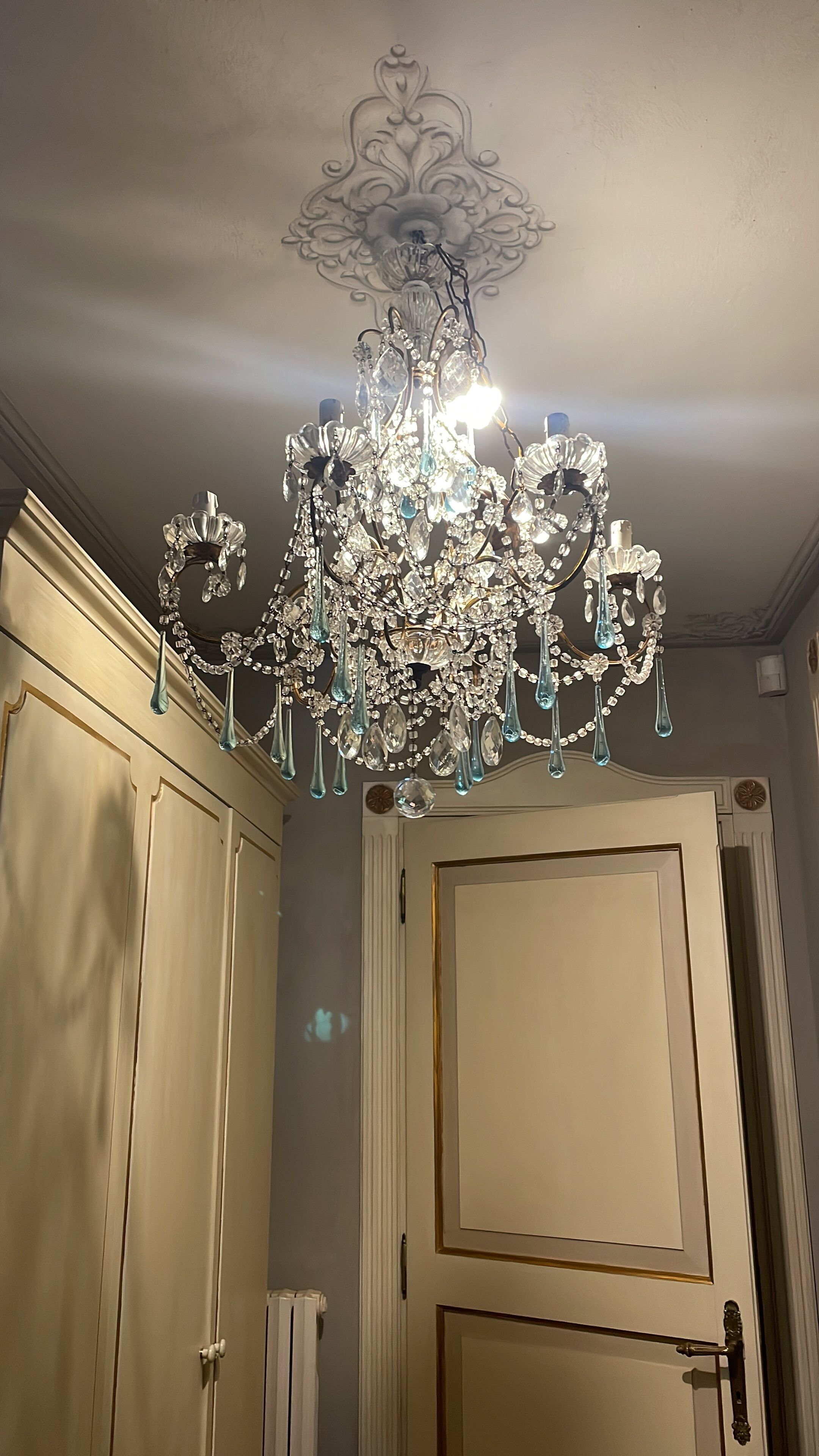 A chandelier with multiple crystal elements and a decorative ceiling medallion.