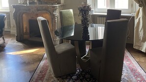 A room with a dining table, four chairs, a large mirror, and a fireplace. - Charming apartment in Piazza Grande Modena (Modena)