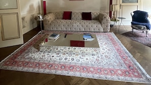 A living room with a tufted sofa, a coffee table, and a patterned rug. - Charming apartment in Piazza Grande Modena (Modena)