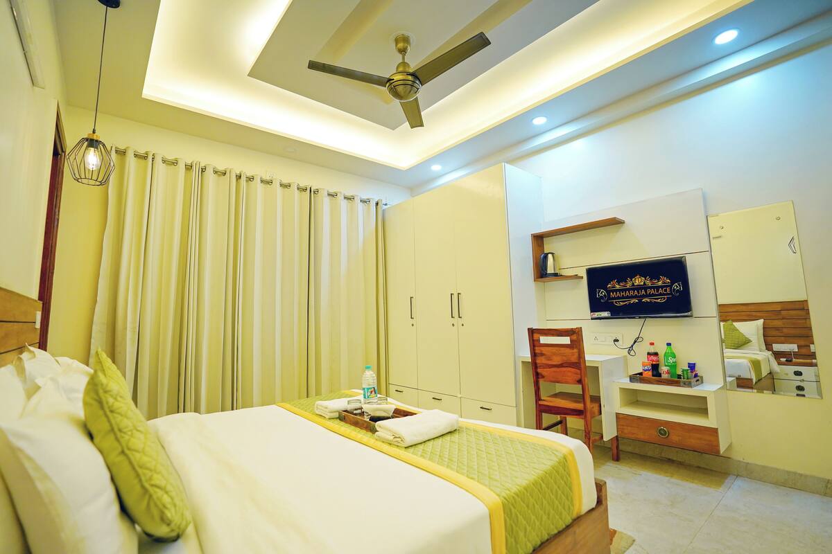 A hotel room with a bed, a desk, a chair, a television, and a ceiling fan.