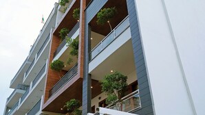 A multi-story building with balconies, a sign reading "Maharaja Palace 81037500", and some greenery on the balconies. - Maharaja Palace Near Medanta Gurgaon  (Gurugram)