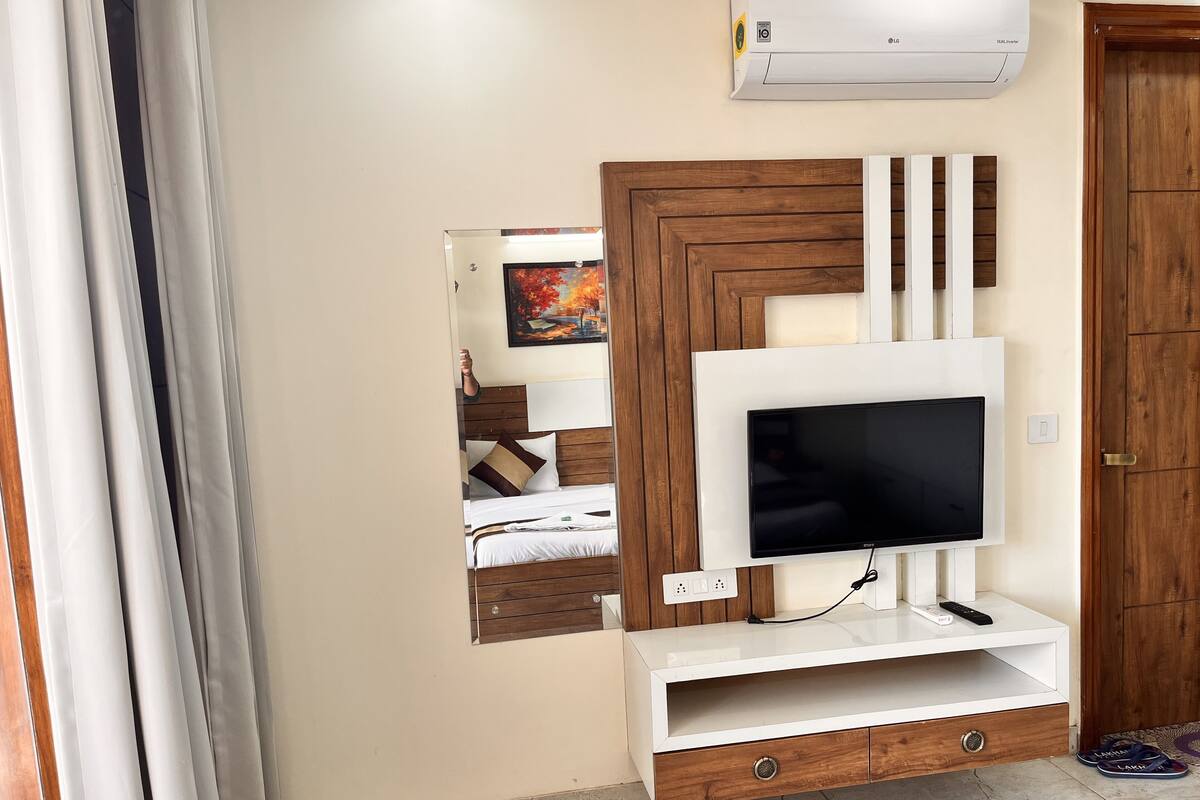 A modern room with a mounted TV, wooden panel wall, and a bed with a headboard.