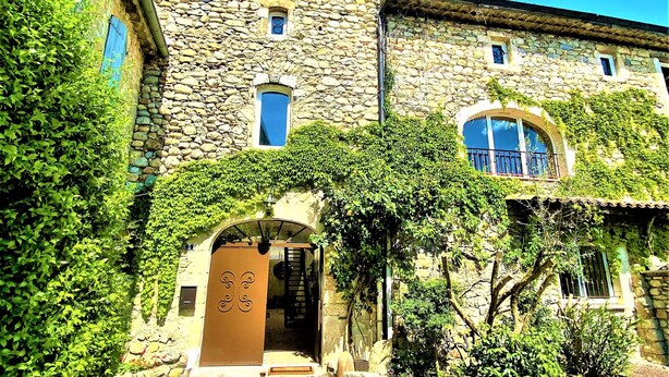 A stone building with a central entrance, a staircase leading to an upper level, and a small balcony. - Gîte 4* for 6p, 3ch, 100m2, HEATED SWIMMING POOL, PATIO (Vallon pont d'arc)