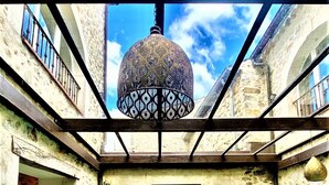 A pool area with a hanging lantern, stone walls, and a view of the sky. - Gîte 4* for 6p, 3ch, 100m2, HEATED SWIMMING POOL, PATIO (Vallon pont d'arc)