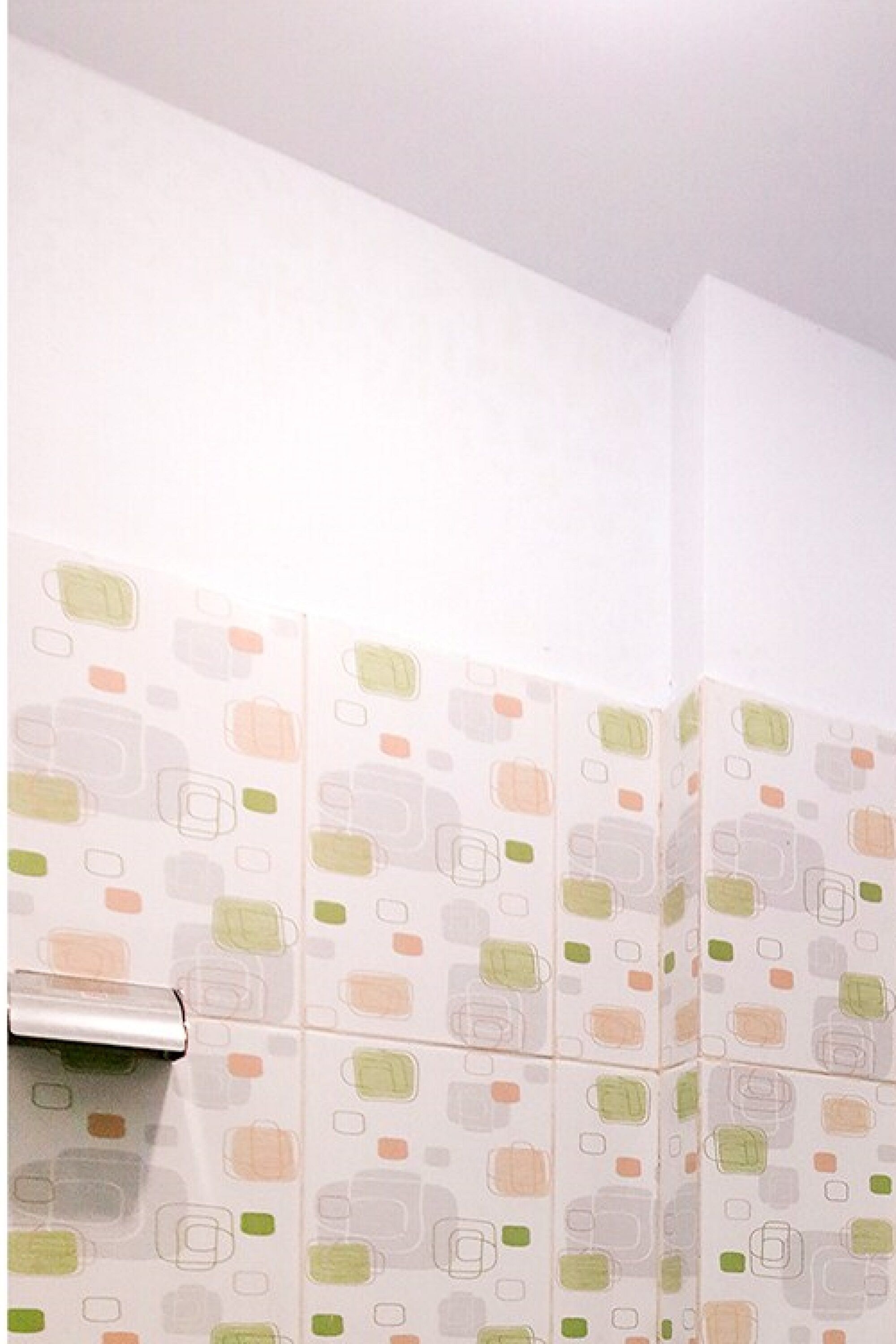 A corner of a room with a patterned wall and a metallic object on the left.