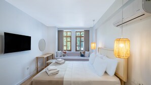 A modern hotel room with a large bed, a TV mounted on the wall, a window seat with curtains, and a hanging lamp. - Audo Studio Hotel (Antalya)