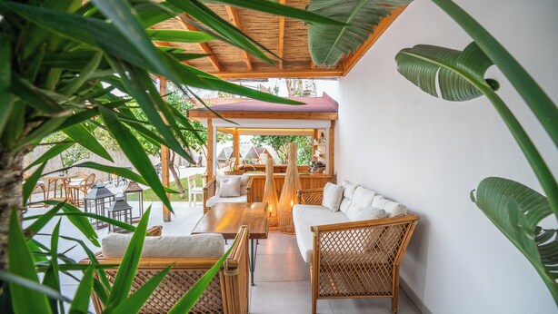 An outdoor seating area with wicker furniture and a wooden pergola. - Audo Studio Hotel (Antalya)