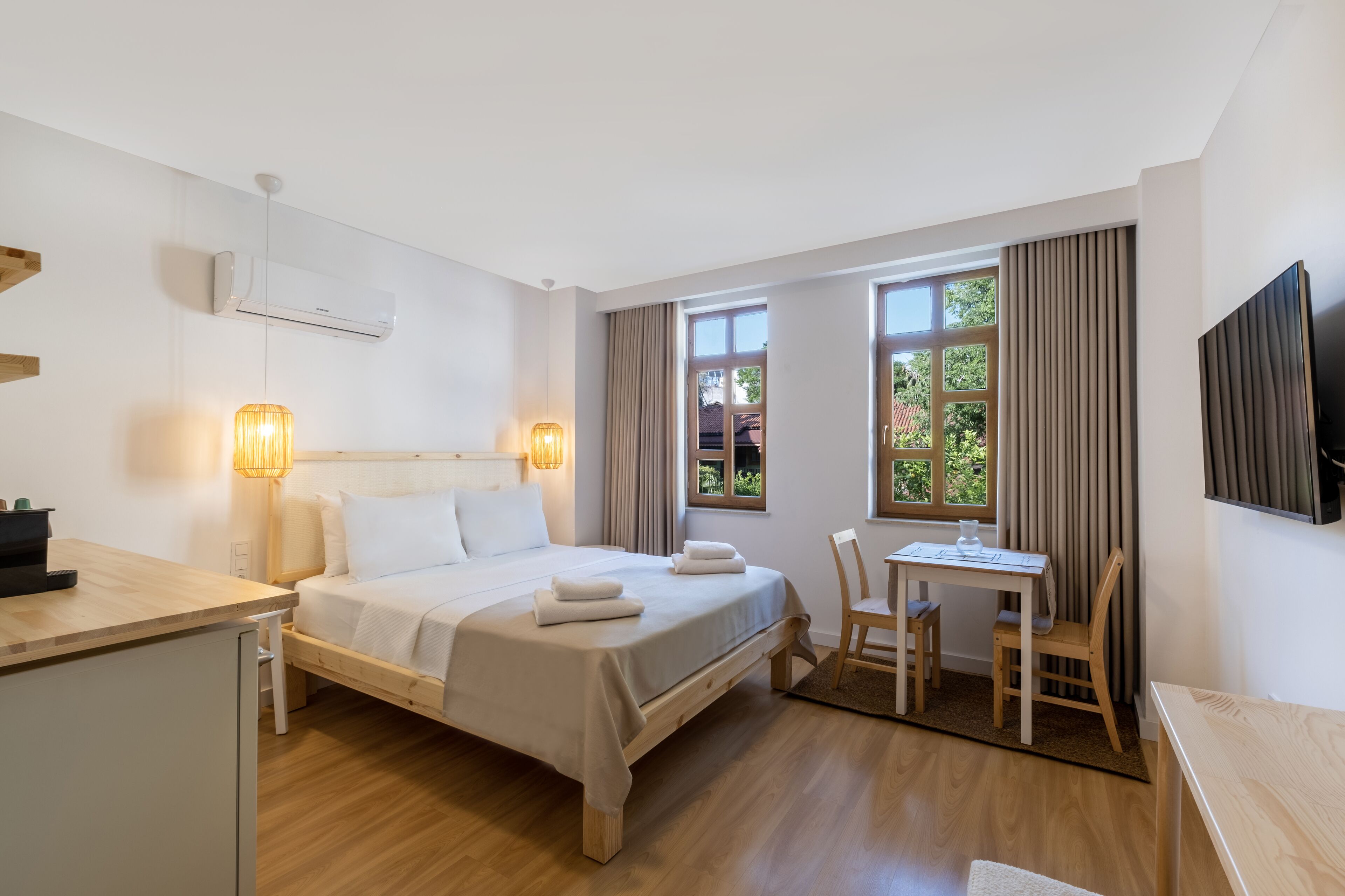 A modern hotel room with a bed, bedside table, desk, and chair.
