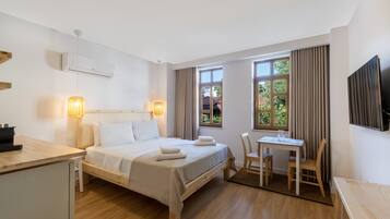 A modern hotel room with a bed, bedside table, desk, and chair.
