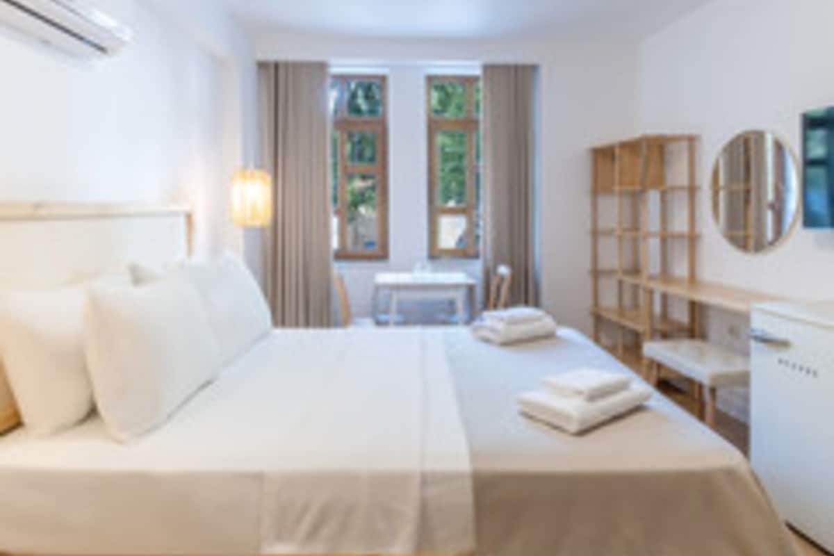 A bedroom with a bed, a desk, a chair, a bookshelf, and a window.