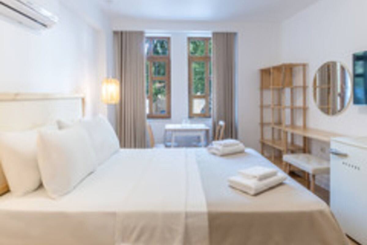 A bedroom with a bed, a desk, a chair, a bookshelf, and a window.