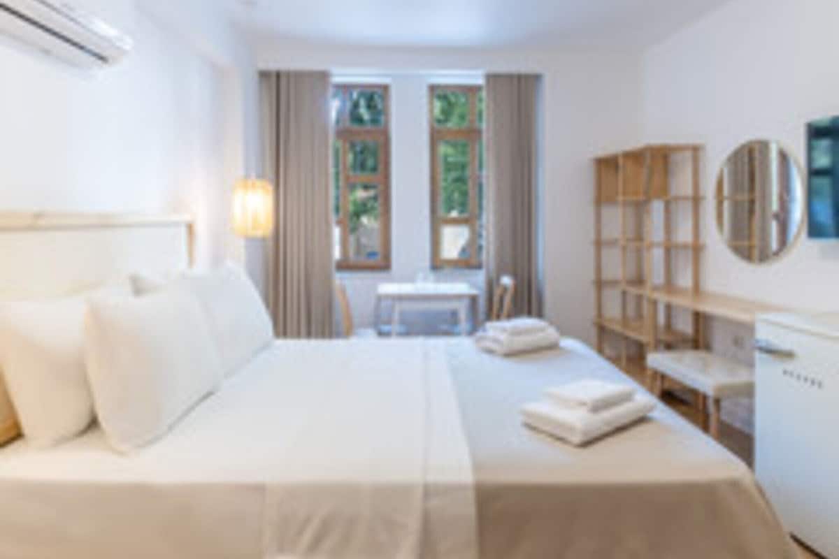 Un dormitorio con cama, escritorio, silla, estantería y ventana.