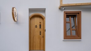 A wooden door with a small window above it, a wooden plaque on the wall, and a set of white steps leading up to the door. - Audo Studio Hotel (Antalya)
